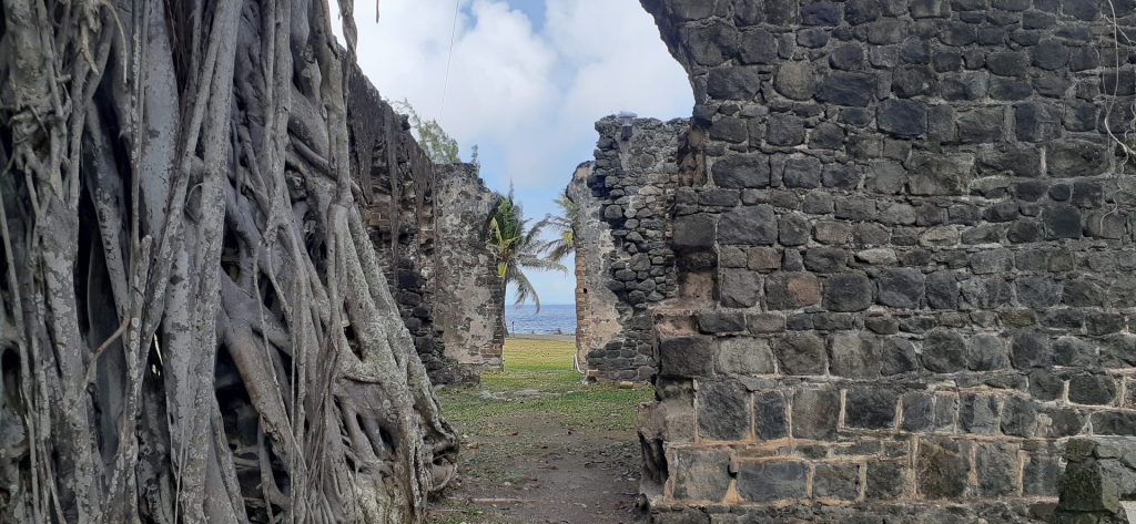 Historic stone walls and archway framing a coastal landscape