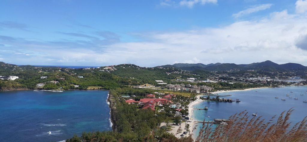 Aerial view of a coastal town with beaches, turquoise water, and surrounding hills