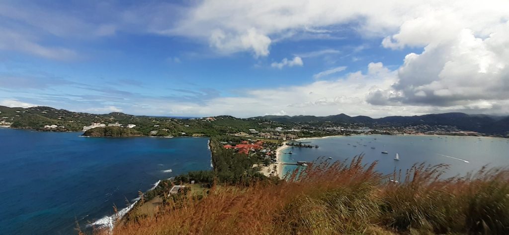 Aerial view of a coastal town with beaches, turquoise water, and surrounding hills