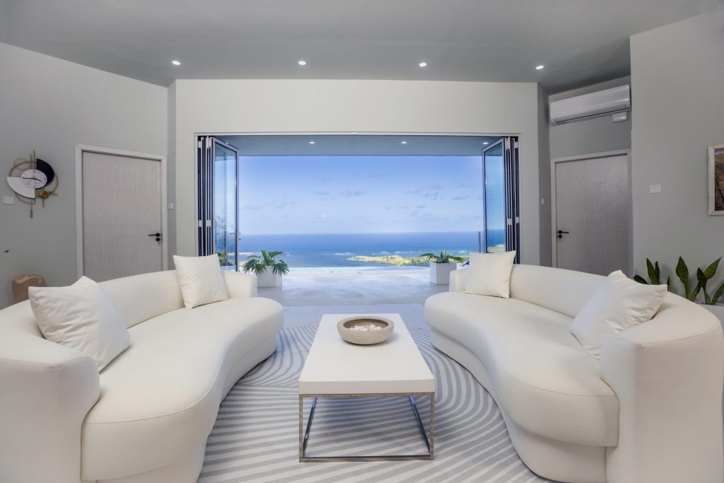 Bright open-plan living room with white sofa, sea view, and modern kitchen